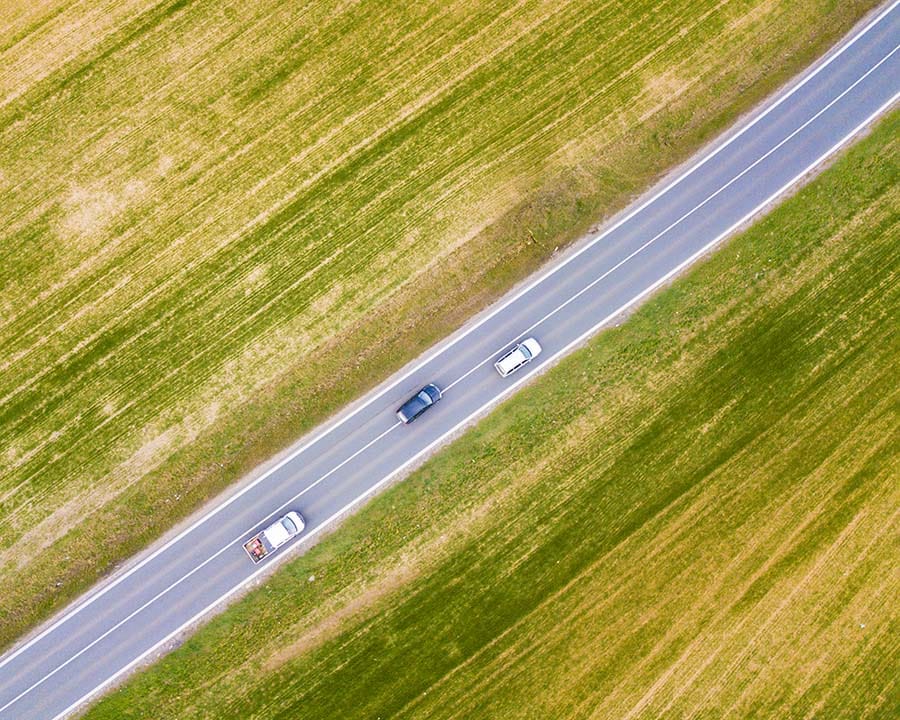 Three cars driving on long stretch on road.