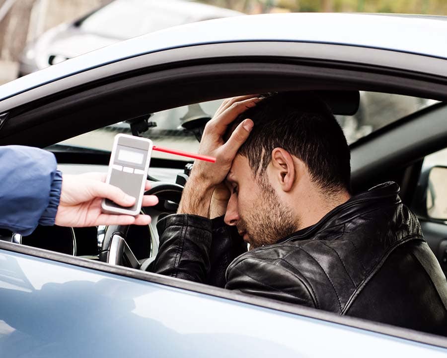 Man with his head in his hands in his car doing a breath test.