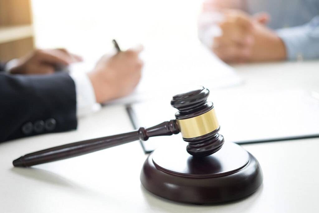 Lawyer and client having a consultation with a gavel in front of them on table.