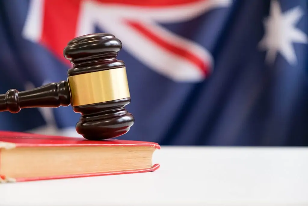 Gavel hitting a book with Australian flag in background.
